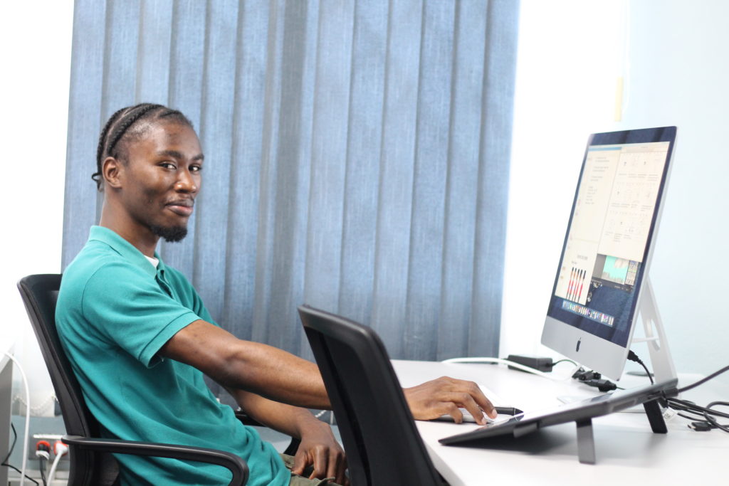 Animation student, at the Vocational Training Development Institute, smiles for the camera while using iMac computer donated by the Advance Program